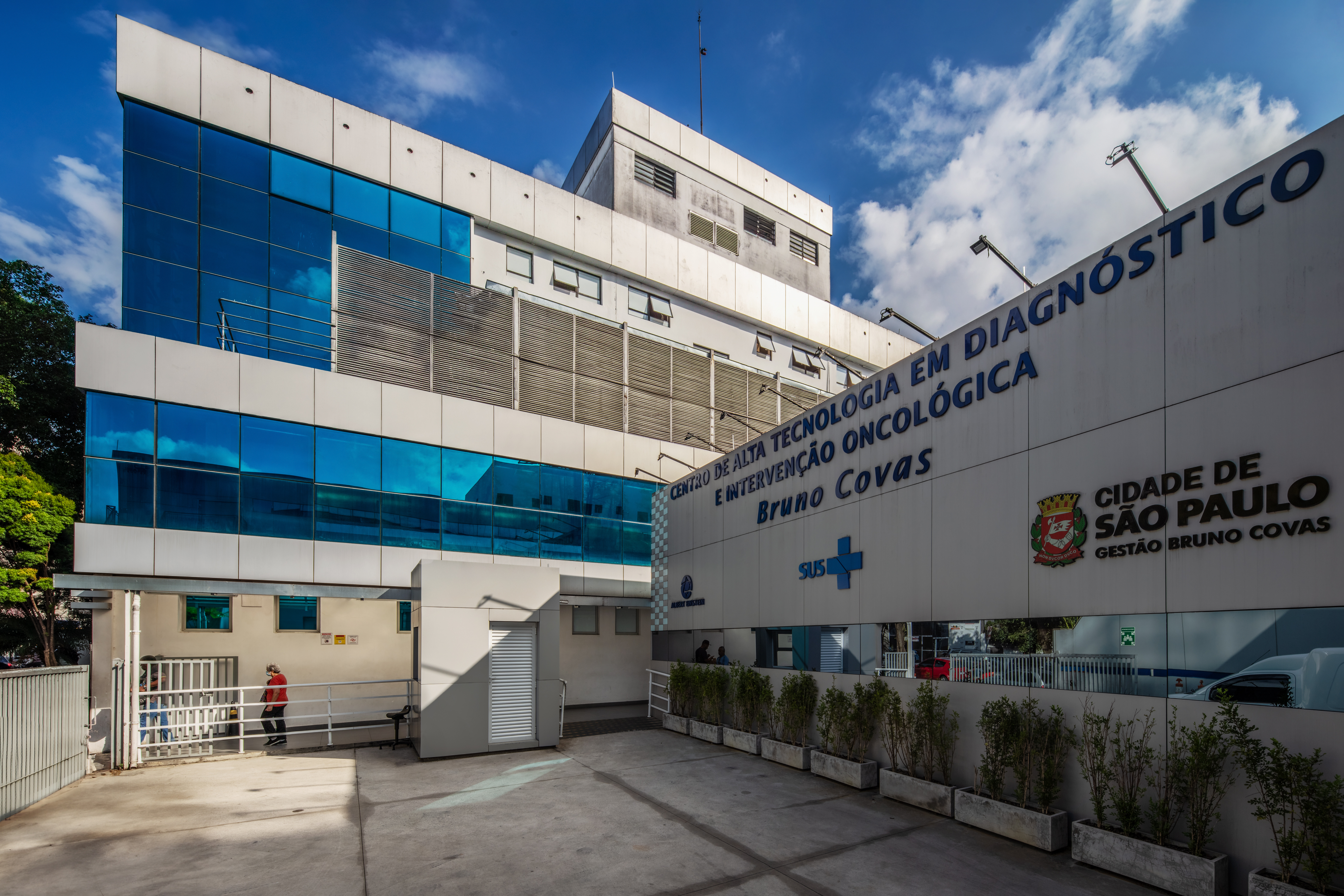 Na foto vê-se a fachada de um prédio, moderno, parcialmente revestida com vidro; em uma de suas faces, lê-se 